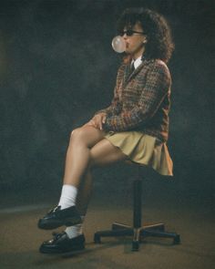 a woman sitting on top of a chair drinking out of a bubble bottle in front of her