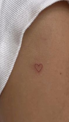 a small heart tattoo on the back of a woman's stomach