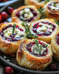 several cranberry rolls on a plate with rosemary sprigs and other holiday foods