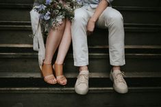 two people sitting on the steps with flowers in their hands and one person holding a bouquet