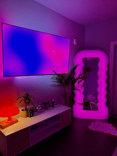 a living room with purple and pink lighting on the wall, television screen above it