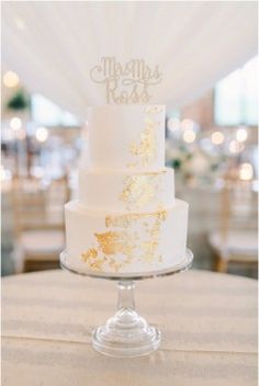 a white and gold wedding cake sitting on top of a table