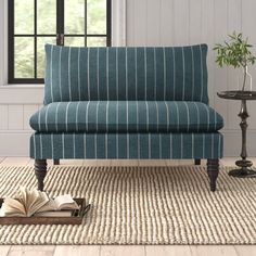 a blue striped couch sitting on top of a rug next to a table with an open book