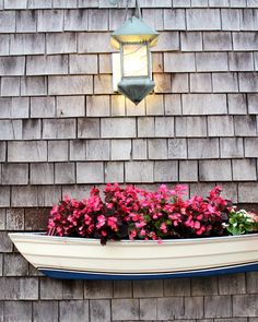 a boat filled with flowers sitting on top of a wooden wall next to a light