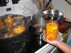 a person holding a jar full of pickles in front of an open stove top