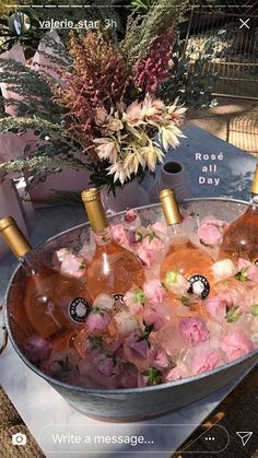 four bottles of rose wine in ice bucket with flowers