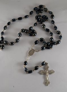 "Vintage 1960's Hematite Beads Beaded Rosary Cross Necklace New Old Stock THIS FABULOUS ROSARY NECKLACE IS VINTAGE 1960'S NEW HOLD STOCK. WE BOUGHT THIS AT A ESTATE OF A LONG TIME COLLECTOR OF RELIGIOUS ITEMS. THE NECKLACE MEASURES APPROX 34\" AND 6\" ON THE TAIL WITH CROSS. FRONT OF CROSS IS JESUS ON THE CROSS" Vintage Silver Beads, Vintage Silver Rosary With Round Beads, Vintage Silver Beaded Necklaces, Rosary Cross, Beaded Rosary, Pocket Watch Antique, Pocket Watch Chain, Rosary Necklace, Hematite Beads