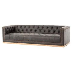 a black leather couch with wooden legs and buttons on the armrests, against a white background