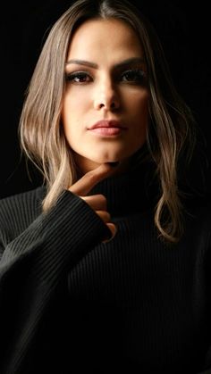 a woman with long hair wearing a black turtle neck sweater and posing for the camera