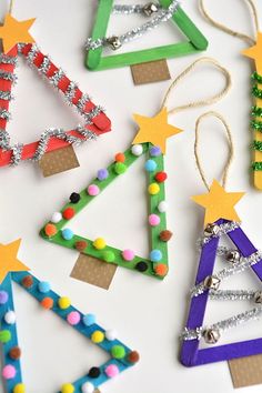 christmas tree ornaments made from popsicle sticks and colored beads on a white surface with string