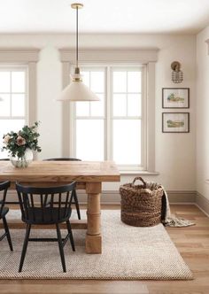 a dining room table with four chairs and a basket on the floor next to it