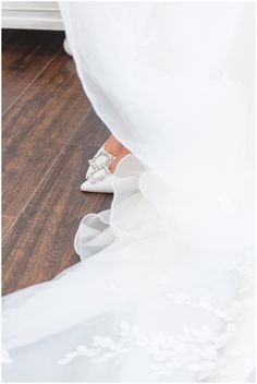 the bride's wedding shoes are on the floor with her veil blowing in the wind