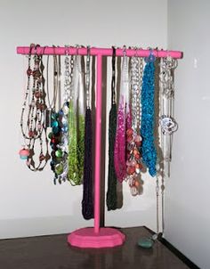 there is a pink jewelry rack with many necklaces hanging from it's sides