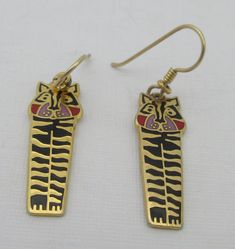 Gold tone dangle stylized tiger earrings that hang from gold tone French wires. The tigers have black, red and lavender enamel on gold tone background. Whimsical and cute, perfect for everyday wear. Some signs of wear.  Signed "Jungle Tiger"  Laurel Burch (c)(r) Measurements: approx. 1.7 inches long & approx. 0.3 inches across (at max)  Please note that due to lighting effects, monitor's brightness, contrast and other settings, there might be some slight differences in the color tone/shade of th Stylized Tiger, Jungle Tiger, Tiger Earrings, Laurel Burch, Pretty Necklaces, Cat Jewelry, Beaded Choker Necklace, French Wire, Color Tone