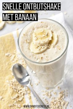 a banana smoothie in a glass on top of a napkin with a spoon next to it