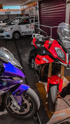 two motorcycles parked next to each other in a parking lot with police cars behind them