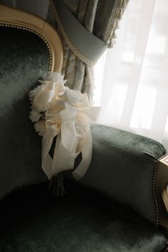 a bouquet of white flowers sitting on top of a green chair next to a window