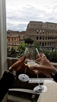 two people toasting wine glasses in front of the colossion