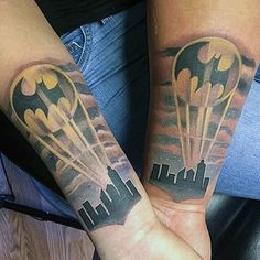 two people with tattoos on their arms holding each other's hands and one has a batman symbol