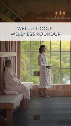 a woman in a bathrobe standing next to two women sitting on benches and looking out the window