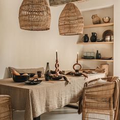 a dining room table with wicker chairs and baskets hanging from the ceiling above it