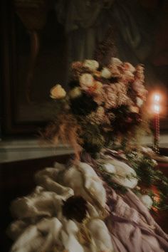 a bouquet of flowers sitting on top of a table next to a candle and some cloth