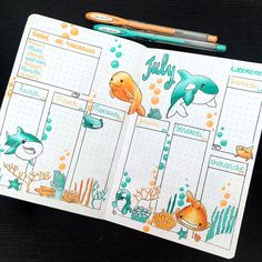 an open planner with dolphins and other marine creatures on the page, next to two pencils