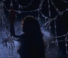 a woman standing in front of a chandelier with lights hanging from it's sides