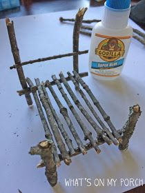 an old chair made out of sticks and glue sitting on top of a white table