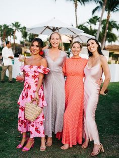 three beautiful women standing next to each other in front of palm trees and umbrellas