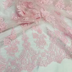 pink and white lace fabric with flowers on the bottom, laying on top of each other