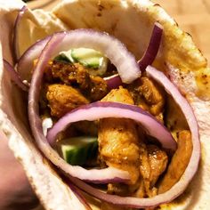 a taco filled with meat and onions on top of a wooden table