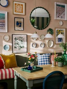 a dining room table with chairs and pictures on the wall above it, along with other decor items