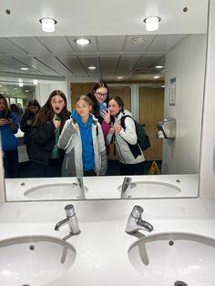 a group of women taking a selfie in front of a bathroom mirror