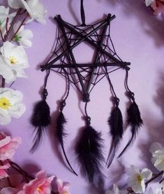 a star shaped dream catcher with feathers and flowers around it on a purple background, surrounded by white orchids