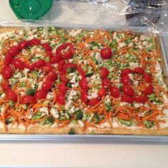 an uncooked pizza with tomatoes, broccoli and cheese