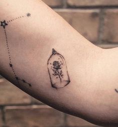 a tattoo on the arm of a person with a rose in a glass bottle and stars