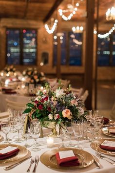 the table is set with place settings, silverware and flowers in centerpieces