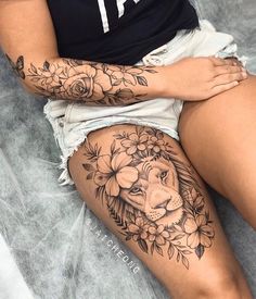 a woman with a lion tattoo on her thigh, sitting in front of a bed