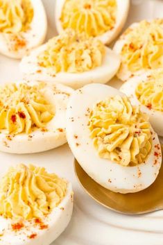 several deviled eggs on a white plate with sprinkles and seasoning