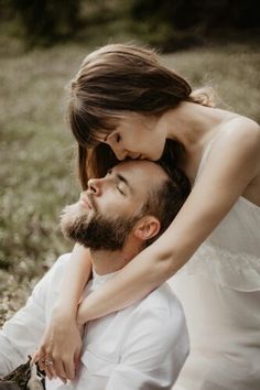 a man holding a woman in his arms while she holds her on the chest and looks at him