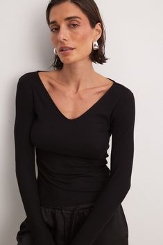 This long sleeve top features a form fit and a ribbed stretchy material. It has a V-neck. Trendy Ribbed Bodycon Top, Winter V-neck Elastane Top, Ribbed V-neck Elastane Top, Trendy Long Sleeve Bodycon Top, Trendy Bodycon Long Sleeve Tops, Black Fitted Long Sleeve V-neck Top, Black Fitted V-neck Long Sleeve Top, Fitted Black V-neck Long Sleeve Top, Bodycon Long Sleeve Tops For Fall