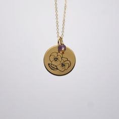 a necklace with a flower on it and a purple bead hanging from the chain