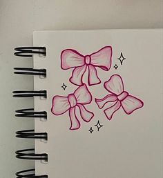 a drawing of three pink bows on a white paper with black marker pens in front of it