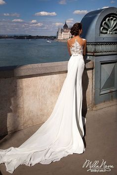 a woman in a long white dress looking out over the water