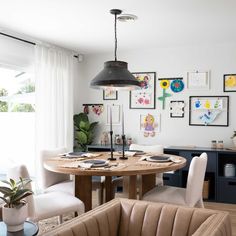 a dining room table with chairs and pictures on the wall