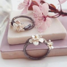 A pretty handmade flower ring based on the Japanese Cherry Blossom in silver and gold. Inspired by Japanese culture and the beautiful cherry blossom, this ring has been hand crafted from sterling silver which has been oxidised to represent the black branches. Cherry blossom has long been symbolic of celebrations and the cycle of life, making this a perfect treat for yourself or a special gift for loved ones. Set with silver blossom with solid gold centres this is a special ring to treasure. Matc Chinese Cherry Blossom, Nature Wedding Ring, Cherry Blossom Ring, Rustic Wedding Rings, Leaf Engagement Ring, Rustic Rings, Floral Engagement Ring, Artisan Rings, Cherry Blossom Flowers