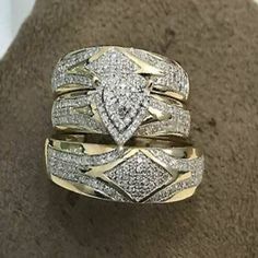 two gold wedding rings with diamonds on top and in the middle, sitting on a carpeted surface