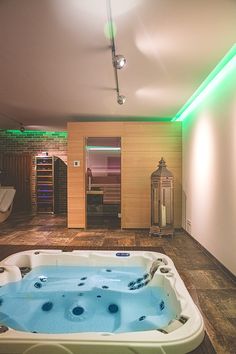 an indoor hot tub is lit up with green lights in the corner and on the wall