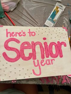 a sign that says here's to senior year next to some scissors and pencils